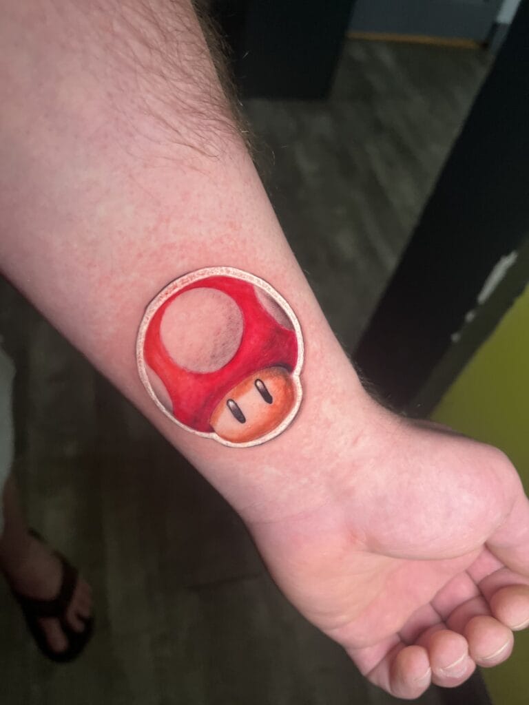 Super Mario Brothers Magic Mushroom 3D Tattoo аз ҷониби Терранс Сойер. Терранс Сойер як рассоми калони татуировка дар Iron Palm Tattoos аст. "Занбӯруғи ҷодугарӣ"-и барҷастае, ки Марио ва бародари ӯро дар бозии видеоии классикии nintendo "супер баланд" мекунад, гуфта мешавад дар асоси занбӯруғи Аманита мускария. Офаридгор Шигеру Миямото баъдтар гуфт, ки "Алиса дар ҷаҳони мӯъҷизот" ба эҷоди тасвири бозӣ таъсир кардааст. .Iron Palm ягона студияи татуировкаи шабона дар Атланта аст.