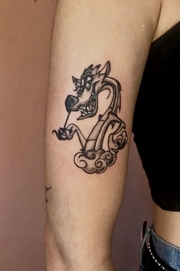 Черная татуировка дракона Мушу в стиле аниме от Вивианы Сааведры. Вивиана — постоянный тату-мастер Iron Palm Tattoos родом из Чили. Мушу — вымышленный персонаж мультфильма Диснея «Мулан».