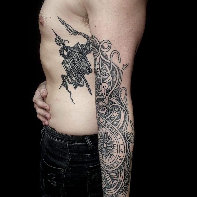 Dua Naga Viking Nordik terjalin di lengan bawah dalam karya khusus ini, menjaga Vegvisir yang kuat—kompas magis Islandia—di pusat komposisi. Seluruh desain dibalut Rune Elder Futhark, diukir dengan gaya tato ukiran yang sangat detail. Arsiran dotwork memberikan kedalaman dan tekstur pada lengan ini sekaligus mempertahankan estetika Nordik kuno. Desain ini menyalurkan tema perlindungan, bimbingan, dan mitologi Viking.