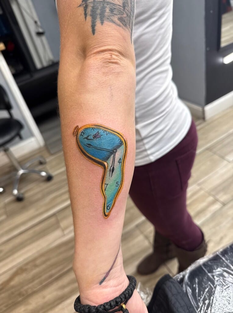 Tattoo sa braso na may kulay na surreal na natutunaw na orasan